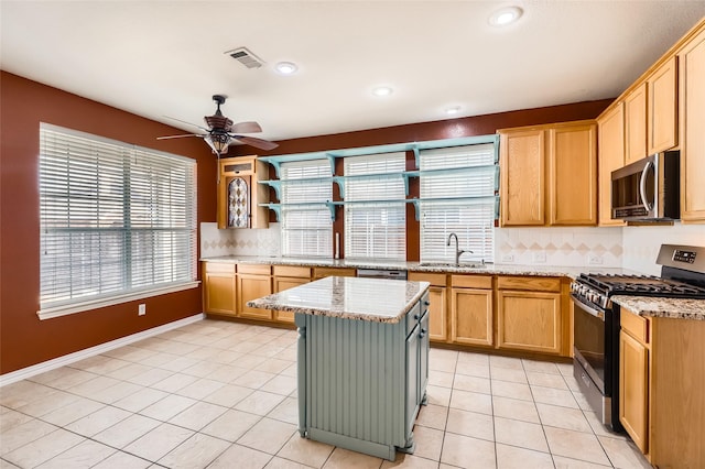 kitchen featuring a center island, decorative backsplash, sink, light stone countertops, and stainless steel appliances