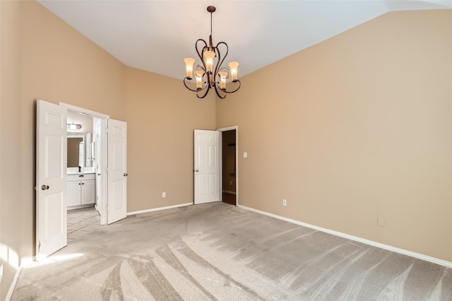 spare room with high vaulted ceiling, light colored carpet, and a notable chandelier