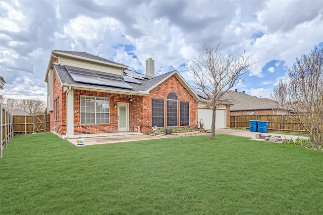 back of house with a patio, solar panels, a yard, and a garage