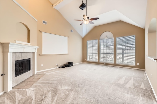 unfurnished living room with ceiling fan, light colored carpet, vaulted ceiling, and a fireplace