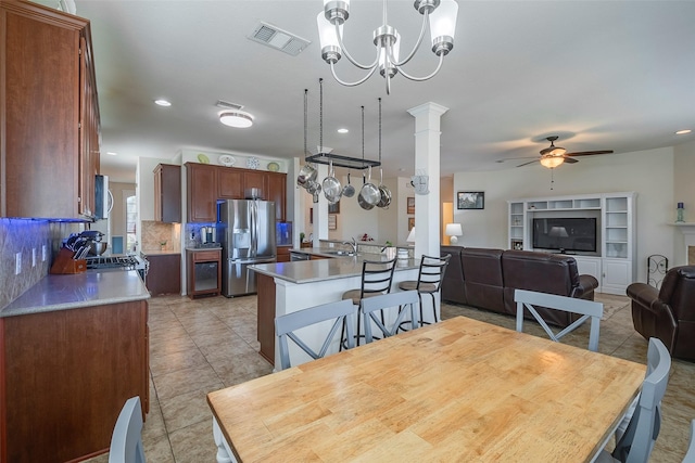 tiled dining area featuring sink, ceiling fan with notable chandelier, and decorative columns