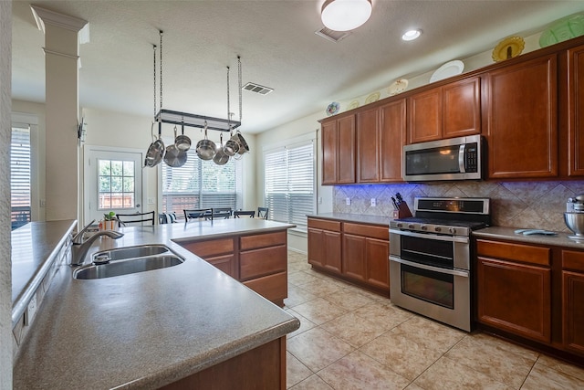 kitchen with stainless steel appliances, a sink, tasteful backsplash, light tile patterned flooring, and recessed lighting