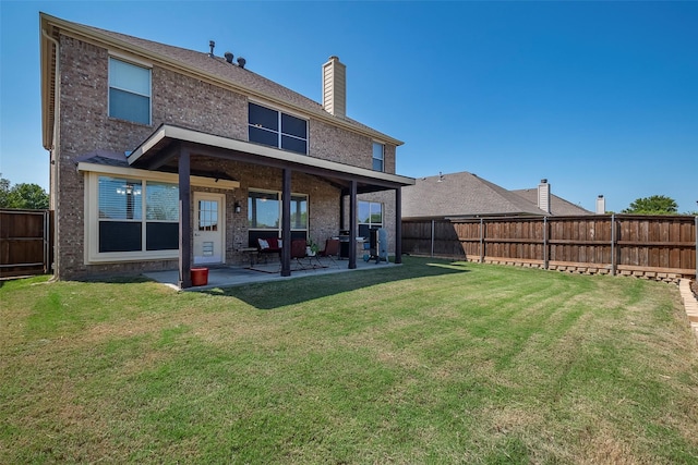 back of property with brick siding, a patio, and a chimney