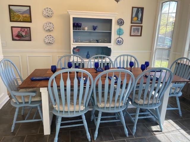 dining space featuring wainscoting, a decorative wall, and tile patterned floors