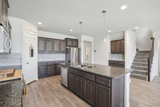 kitchen with appliances with stainless steel finishes, dark brown cabinets, backsplash, and hanging light fixtures