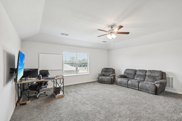 carpeted office space with ceiling fan and a raised ceiling