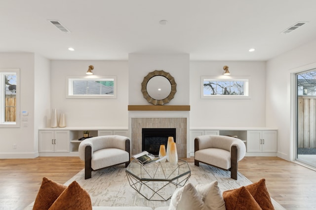 living room with a healthy amount of sunlight, light wood-type flooring, and a tile fireplace