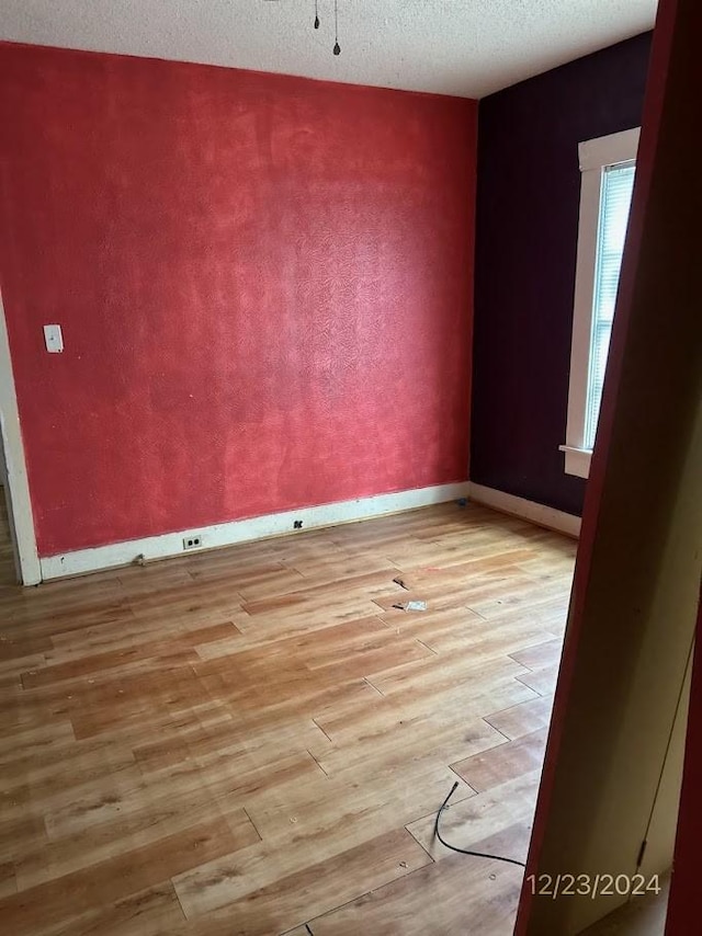 spare room with light wood-type flooring and a textured ceiling