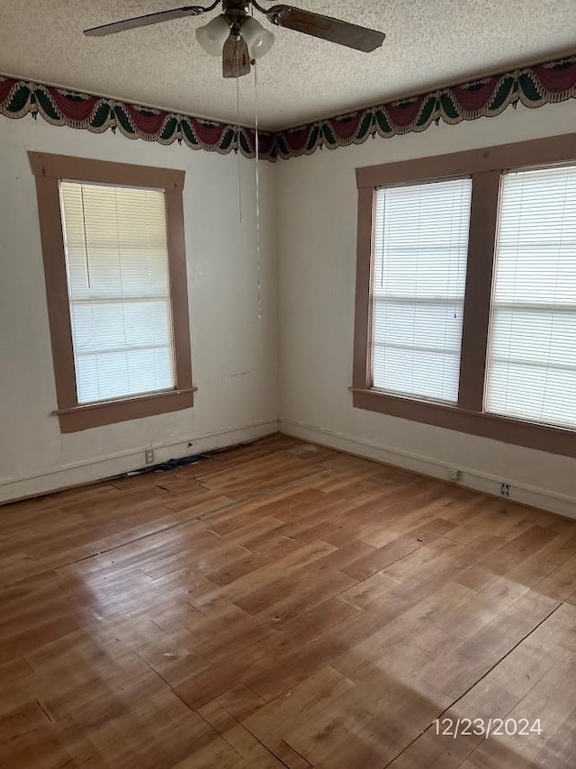 unfurnished room with ceiling fan, wood-type flooring, and a textured ceiling