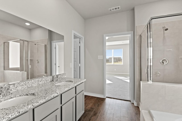 bathroom featuring wood finished floors, a sink, visible vents, and a shower stall