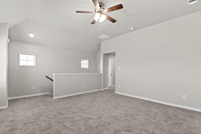 empty room with baseboards, visible vents, ceiling fan, vaulted ceiling, and carpet flooring