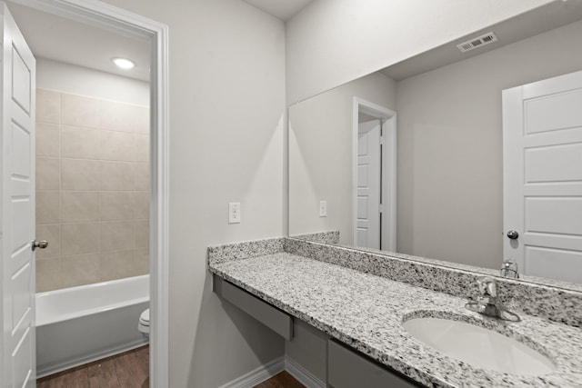 bathroom with visible vents, toilet, vanity, wood finished floors, and baseboards