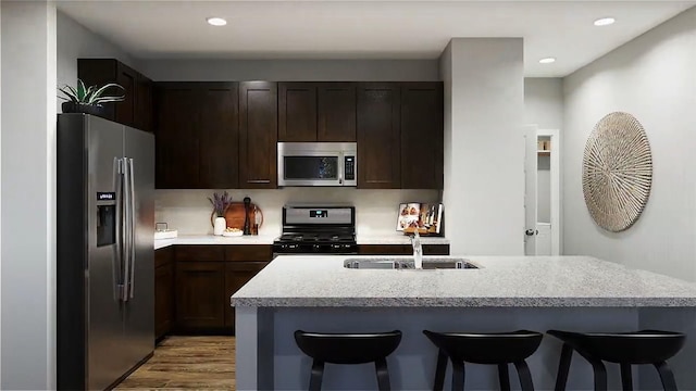 10576 Taruca Dr, Fort Worth, TX 76036 - kitchen featuring appliances with stainless steel finishes, a sink, a breakfast bar area, light wood-type flooring, and recessed lighting