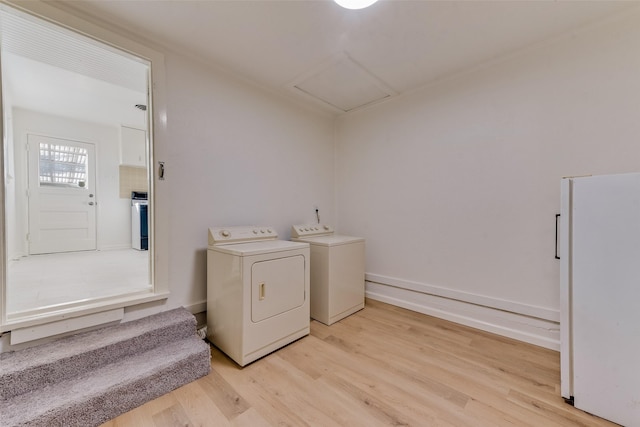 clothes washing area with independent washer and dryer and light wood-type flooring