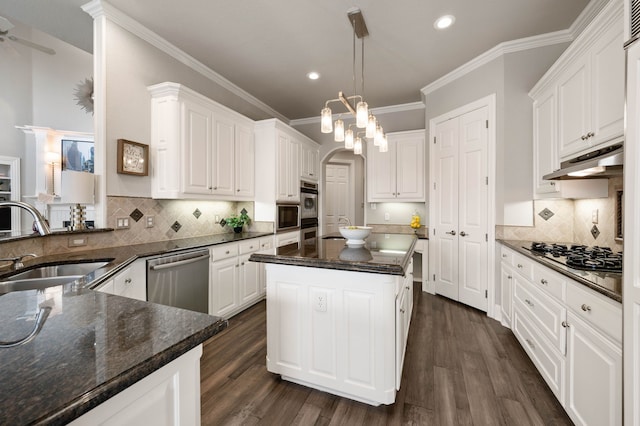 kitchen with kitchen peninsula, sink, white cabinets, decorative backsplash, and stainless steel appliances