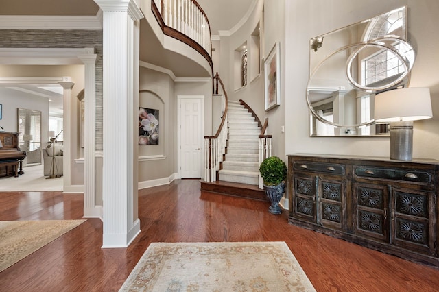 entrance foyer with decorative columns, dark wood-type flooring, and ornamental molding