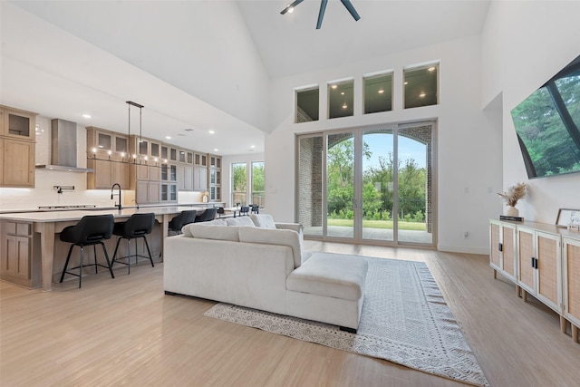 living area with high vaulted ceiling, recessed lighting, light wood-style flooring, and baseboards