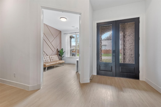 foyer entrance featuring baseboards, wood finished floors, and french doors