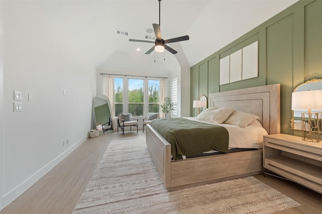 bedroom with lofted ceiling, light wood-style flooring, visible vents, and baseboards