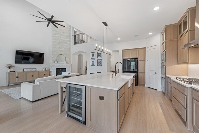 kitchen featuring wall chimney exhaust hood, stainless steel appliances, backsplash, a large island, and light hardwood / wood-style flooring