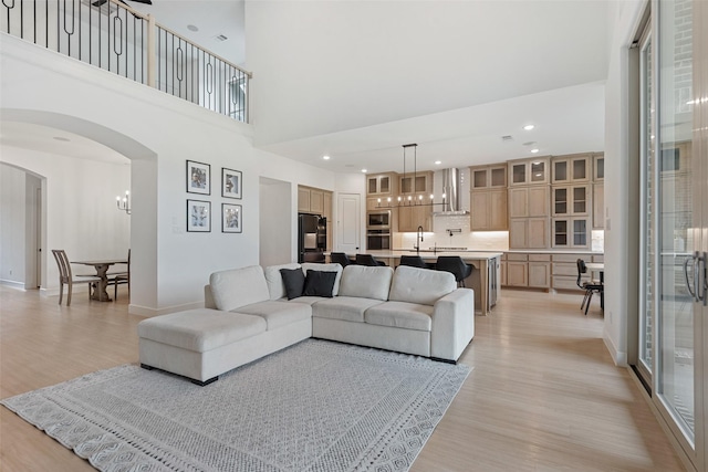 living room featuring arched walkways, light wood finished floors, recessed lighting, a chandelier, and baseboards