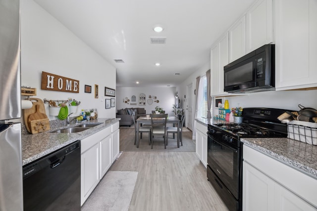 kitchen with white cabinets, sink, light hardwood / wood-style flooring, and black appliances