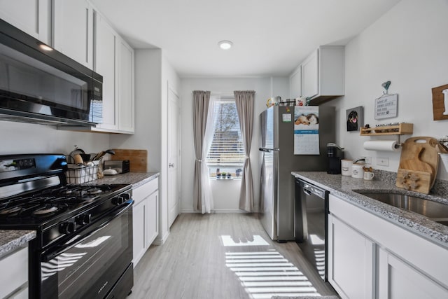 kitchen featuring sink, white cabinetry, light stone counters, light hardwood / wood-style flooring, and black appliances