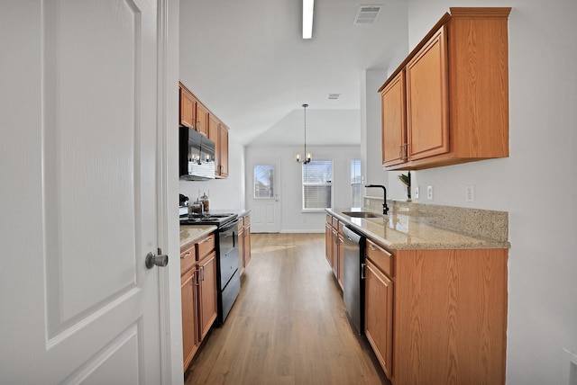 kitchen with stainless steel appliances, light stone countertops, pendant lighting, light hardwood / wood-style flooring, and sink