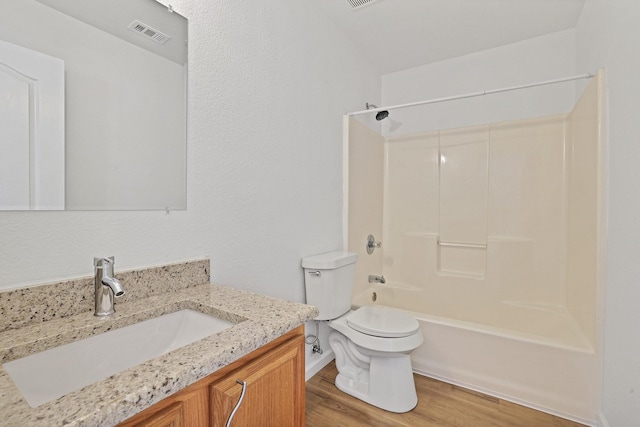 full bathroom with wood-type flooring, washtub / shower combination, vanity, and toilet