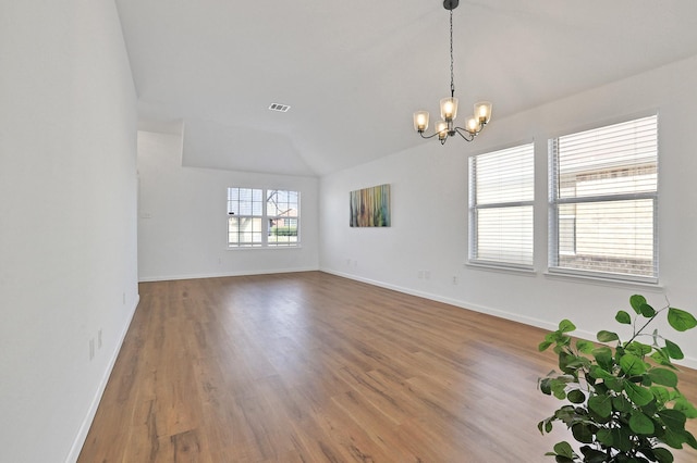 spare room featuring vaulted ceiling, a notable chandelier, and hardwood / wood-style floors