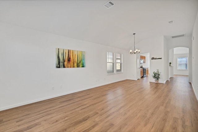 empty room featuring vaulted ceiling, an inviting chandelier, and light hardwood / wood-style flooring