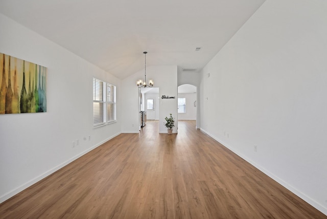 unfurnished living room featuring wood-type flooring, lofted ceiling, and an inviting chandelier