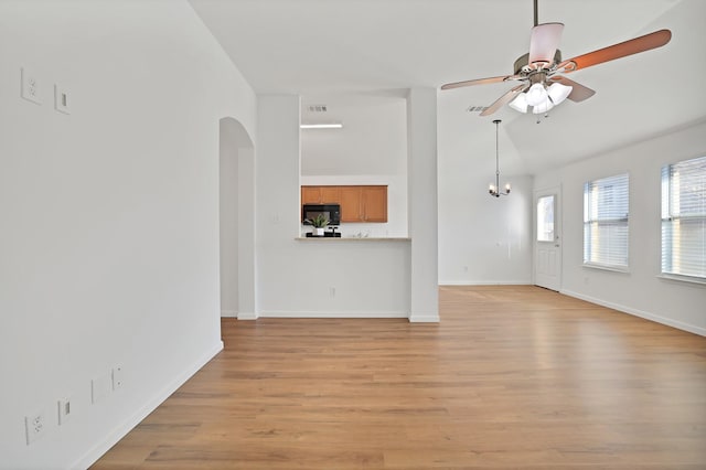 unfurnished living room featuring ceiling fan with notable chandelier, light hardwood / wood-style flooring, and lofted ceiling