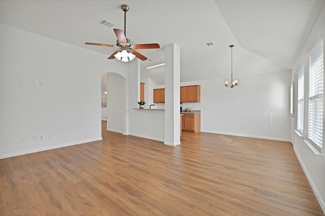 unfurnished living room featuring vaulted ceiling, ceiling fan with notable chandelier, and light hardwood / wood-style flooring