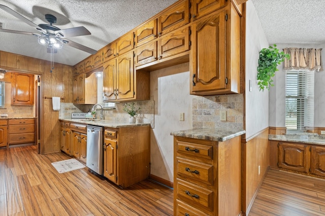 kitchen with light stone counters, dishwasher, ceiling fan, and light hardwood / wood-style flooring