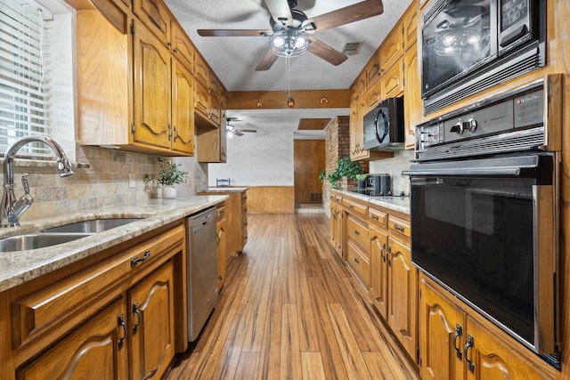 kitchen with a textured ceiling, black appliances, sink, backsplash, and light hardwood / wood-style flooring