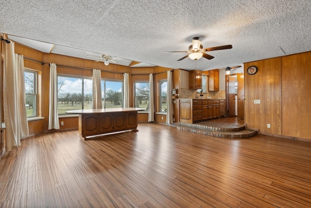 unfurnished living room featuring ceiling fan, wood walls, and hardwood / wood-style flooring