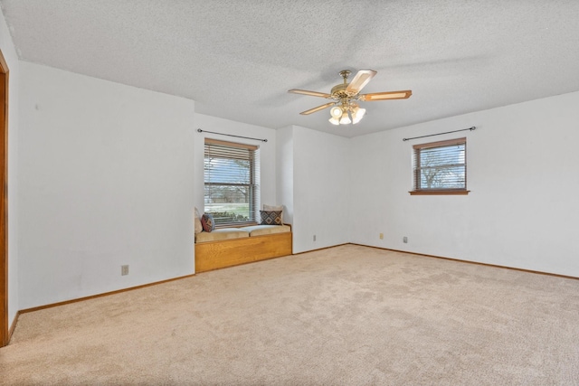 carpeted empty room featuring a textured ceiling, ceiling fan, and a wealth of natural light