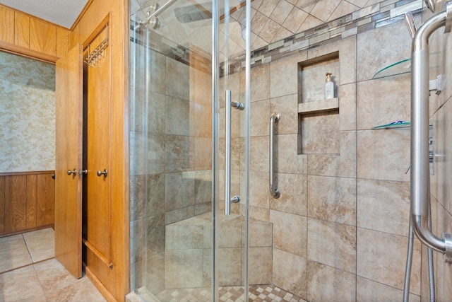 bathroom with a shower with shower door and wooden walls