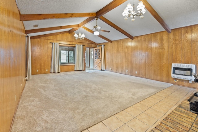 unfurnished living room featuring vaulted ceiling with beams, wooden walls, heating unit, a textured ceiling, and light carpet