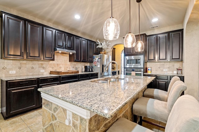 kitchen featuring decorative light fixtures, sink, and an island with sink