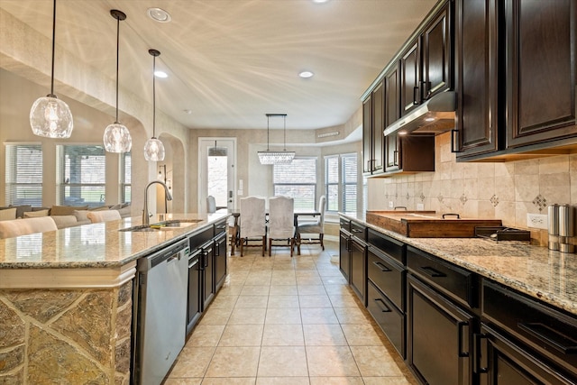 kitchen with light stone counters, sink, hanging light fixtures, and stainless steel dishwasher