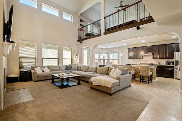 living room with ceiling fan, a high ceiling, and light tile patterned flooring