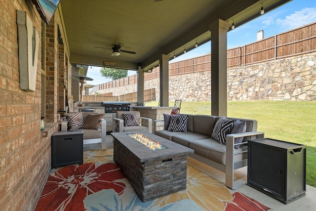 view of patio / terrace with an outdoor kitchen, ceiling fan, and an outdoor living space with a fire pit