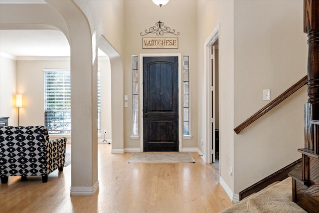 foyer entrance featuring crown molding and light wood-type flooring