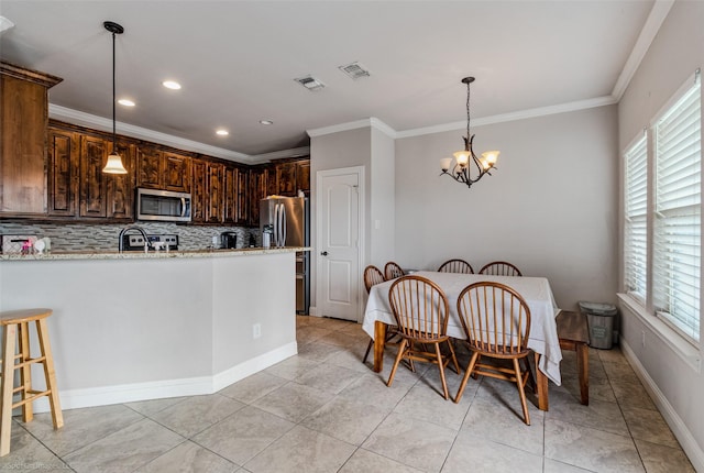 kitchen with hanging light fixtures, backsplash, light stone countertops, and appliances with stainless steel finishes