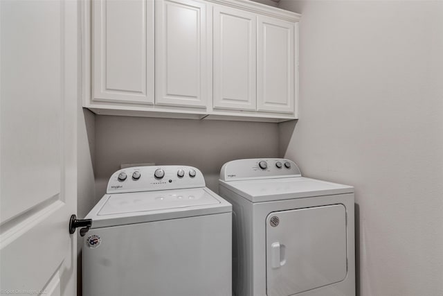 clothes washing area featuring cabinets and separate washer and dryer