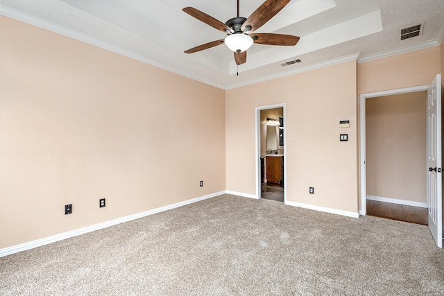 unfurnished bedroom featuring ornamental molding, ceiling fan, ensuite bath, and a tray ceiling