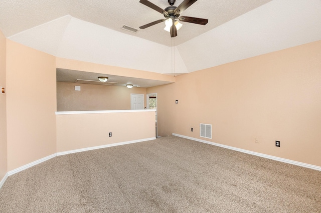 carpeted empty room featuring ceiling fan, vaulted ceiling, and a textured ceiling