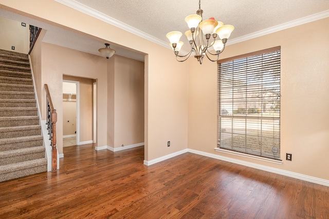 empty room featuring an inviting chandelier, ornamental molding, dark hardwood / wood-style flooring, and a textured ceiling